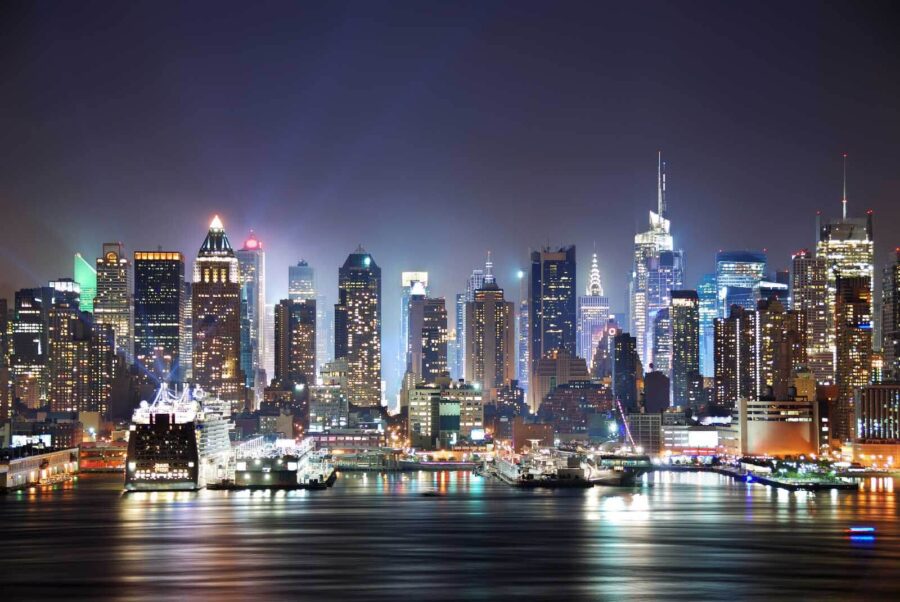 City skyline at night with lights reflecting on water