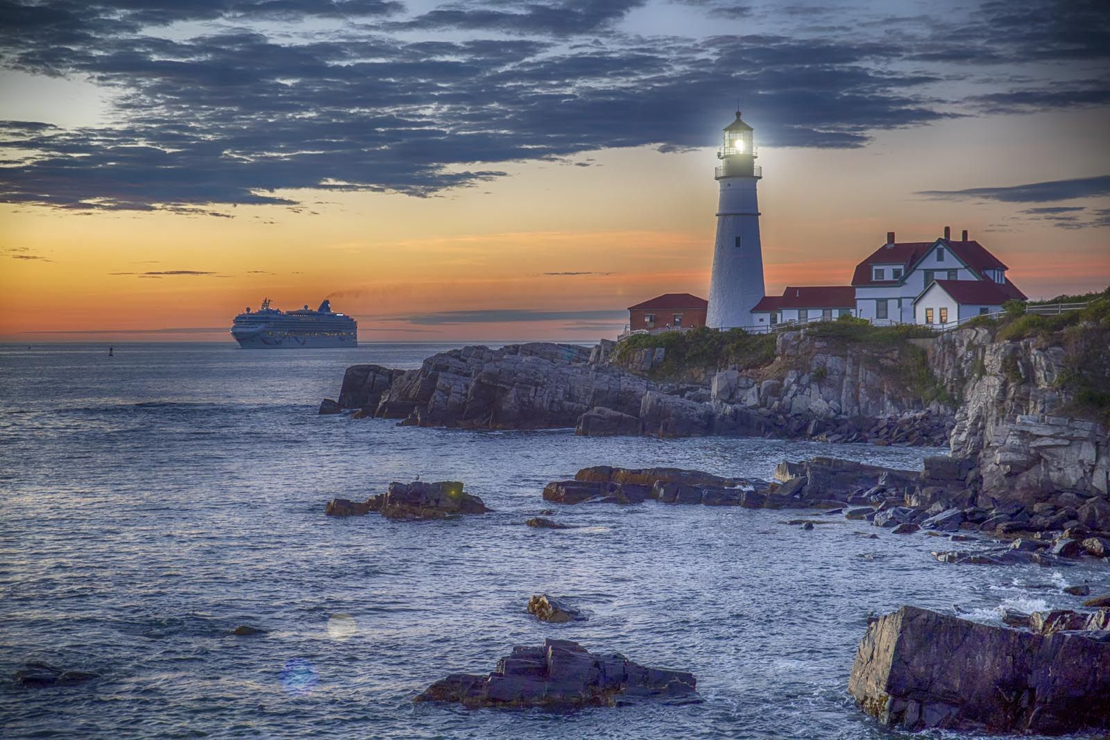 u10328p - Lighthouse on a rocky shore with a cruise ship in the background - tegory