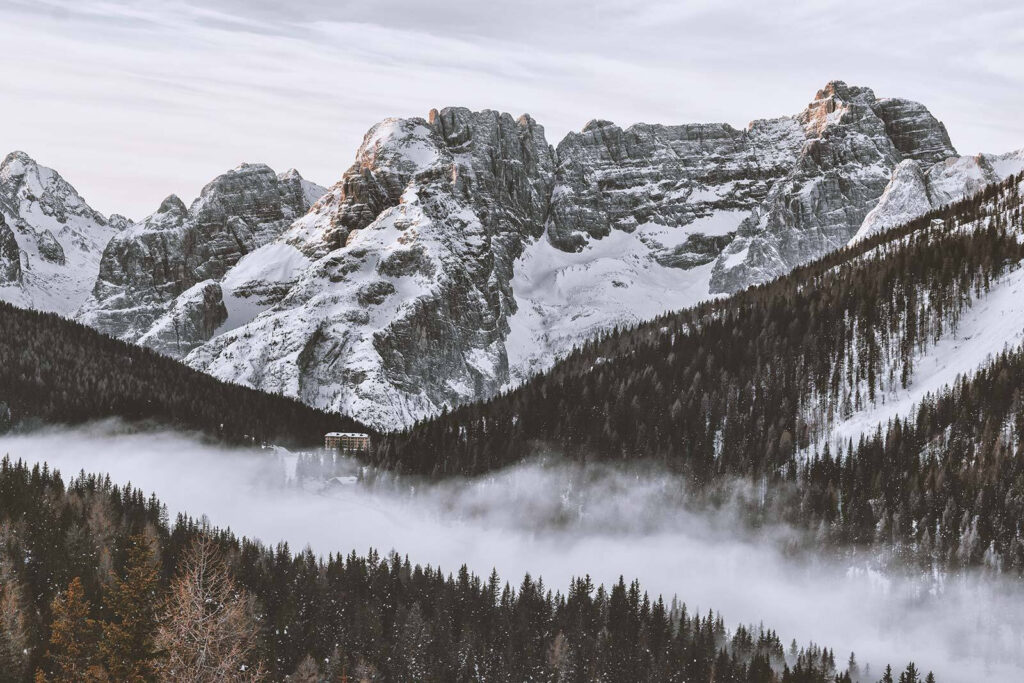 Snowy mountain range with trees and a building