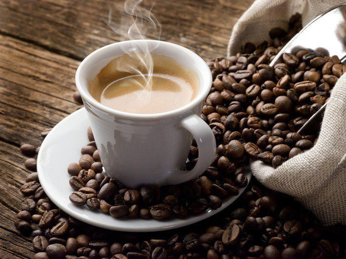 Cup of coffee on a saucer with coffee beans