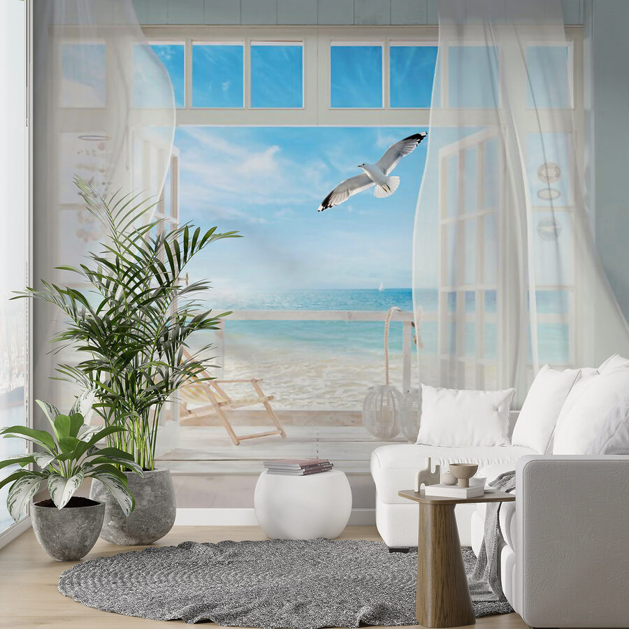 View of a beach from a room with a bird flying over it